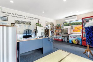 Ein Empfangsbereich mit Schreibtisch, Computer und einer Wand mit einem Panoramoplakat. Es gibt Pflanzen, einen Tip Top Eisautomaten und eine Auswahl an Snacks.