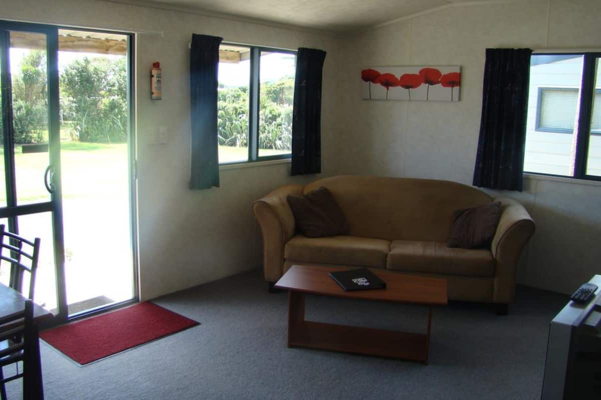 Een woonkamer met een bank, een salontafel en een deur die uitkomt op een balkon.