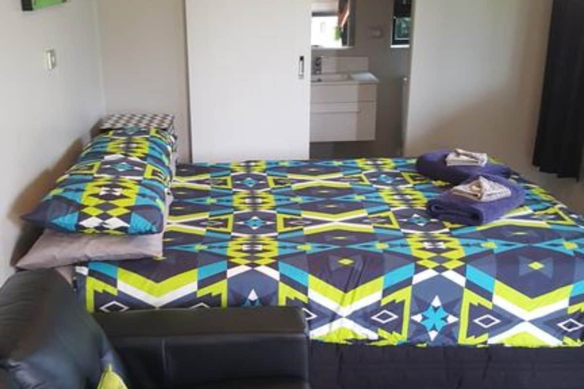 Ein Schlafzimmer mit einem Bett, einer Schlafcouch, einem kleinen Tisch und einer Küchenzeile.