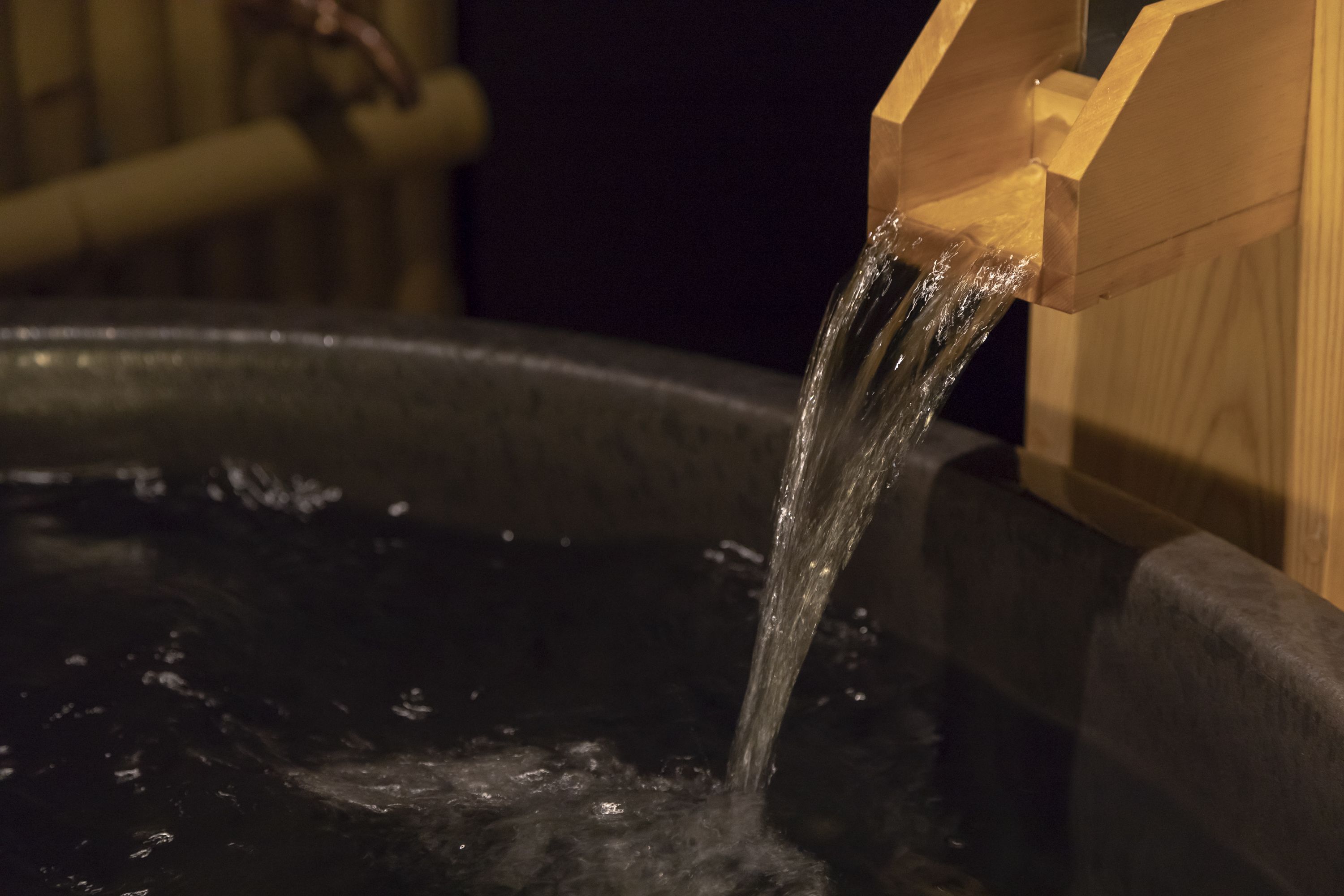 A wooden structure with water flowing from it into a dark basin.