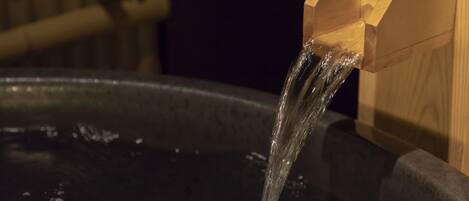 A wooden structure with water flowing from it into a dark basin.