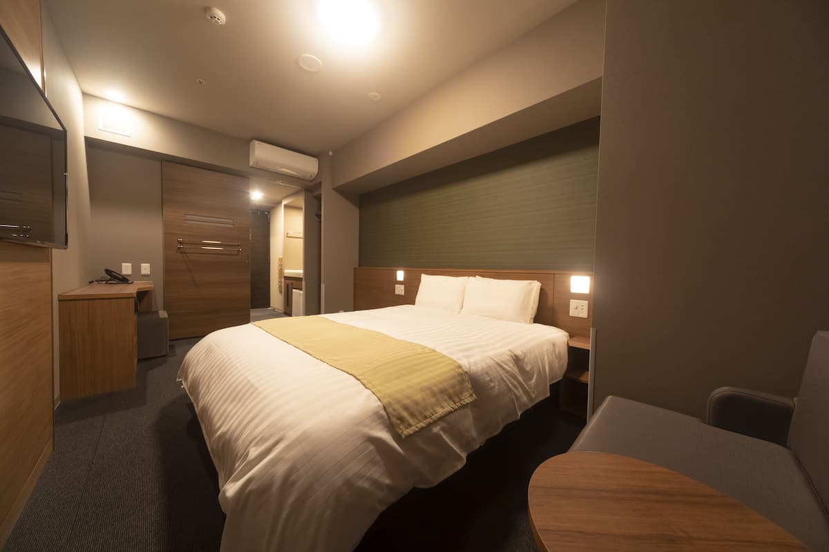 Ein Hotelzimmer mit einem großen Bett, Nachttischen, einem Schreibtisch und einem Sessel.
