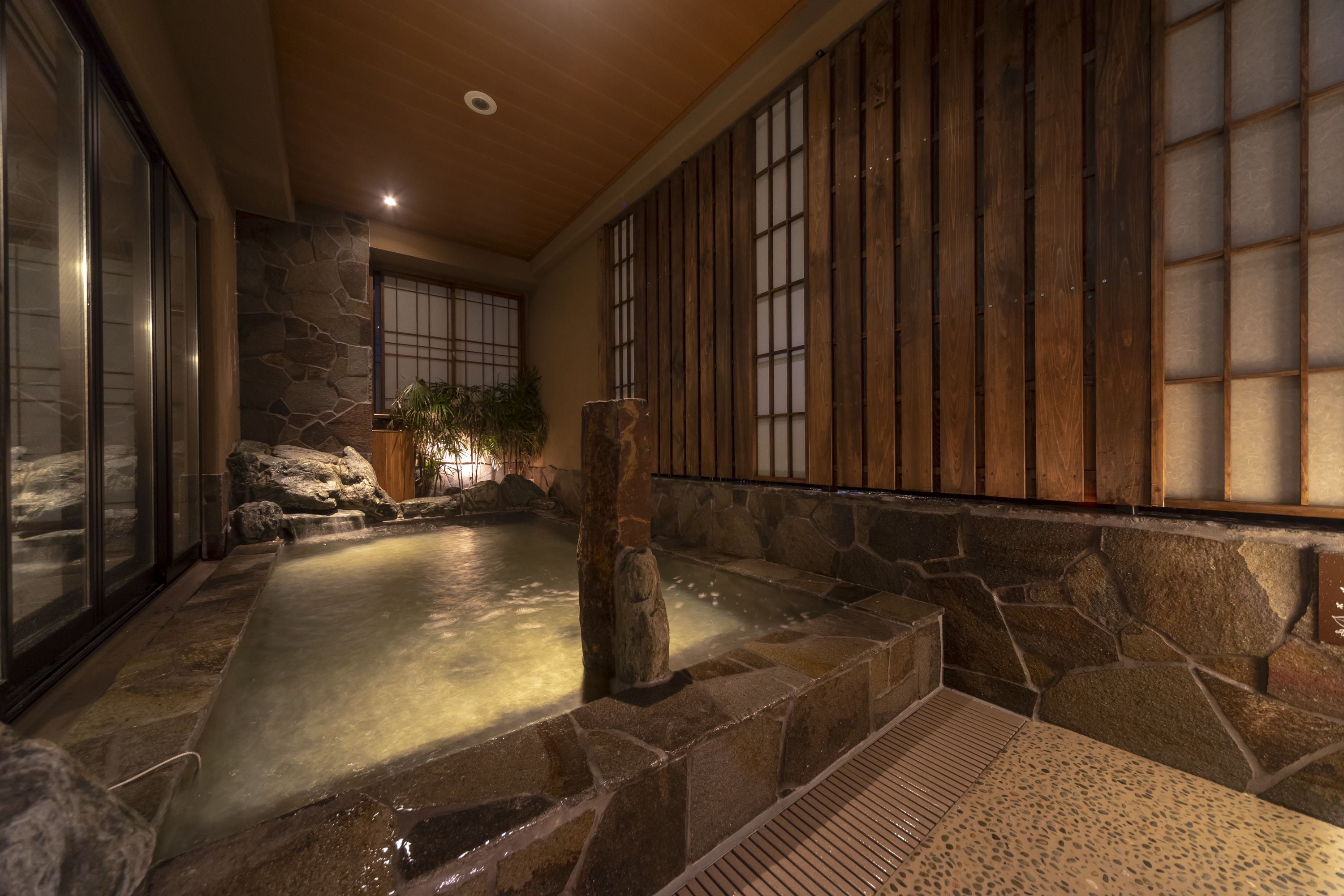 A spa area with a stone pool, wooden walls, and a tiled floor.