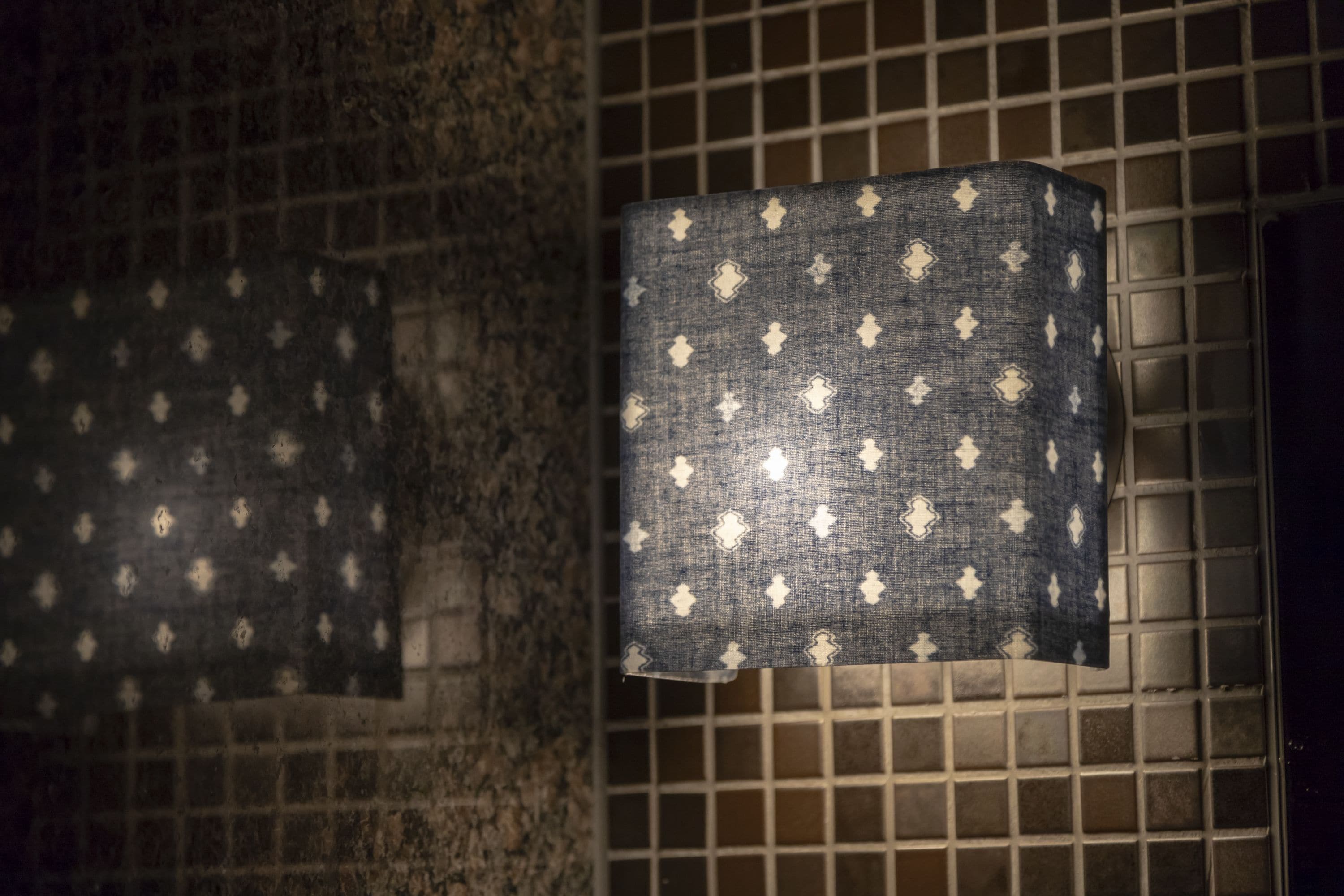 Un baño con pared de azulejos y una toalla colgada en un perchero.