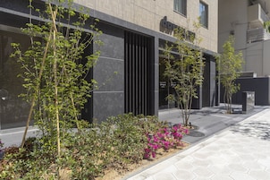 Een modern gebouw met een geometrisch gevelontwerp, buitenplanten en een geplaveid voetpad.