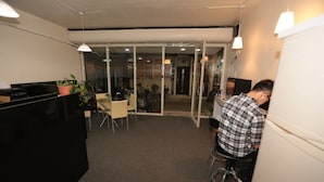 Una oficina pequeña con un escritorio, sillas y una persona trabajando en una computadora.