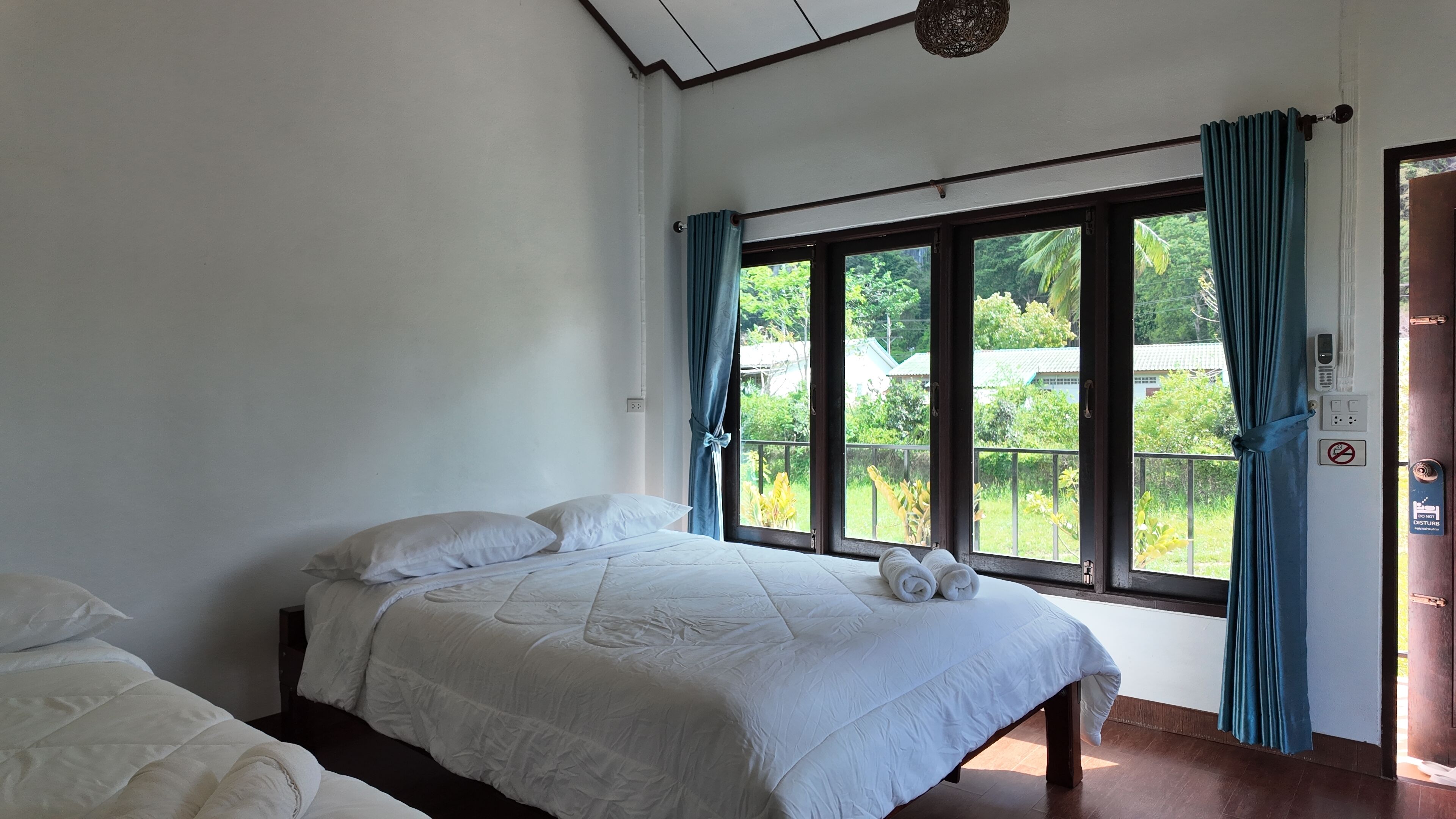 Un dormitorio con cama, ventana con cortinas y vistas a zonas verdes.