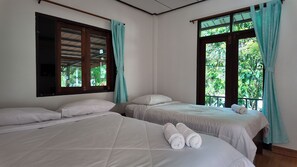 Une chambre avec deux lits, une fenêtre avec des rideaux et une vue sur la verdure.