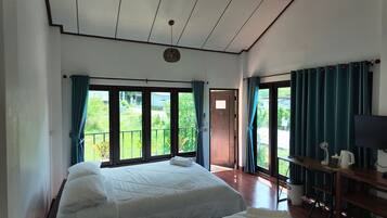 A bedroom with a bed, a TV, a coffee maker, and a view of greenery outside.