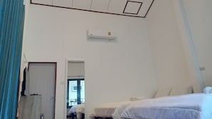 Habitación de hotel con dos camas, una lámpara en el techo, un equipo de aire acondicionado y una ventana con vistas.