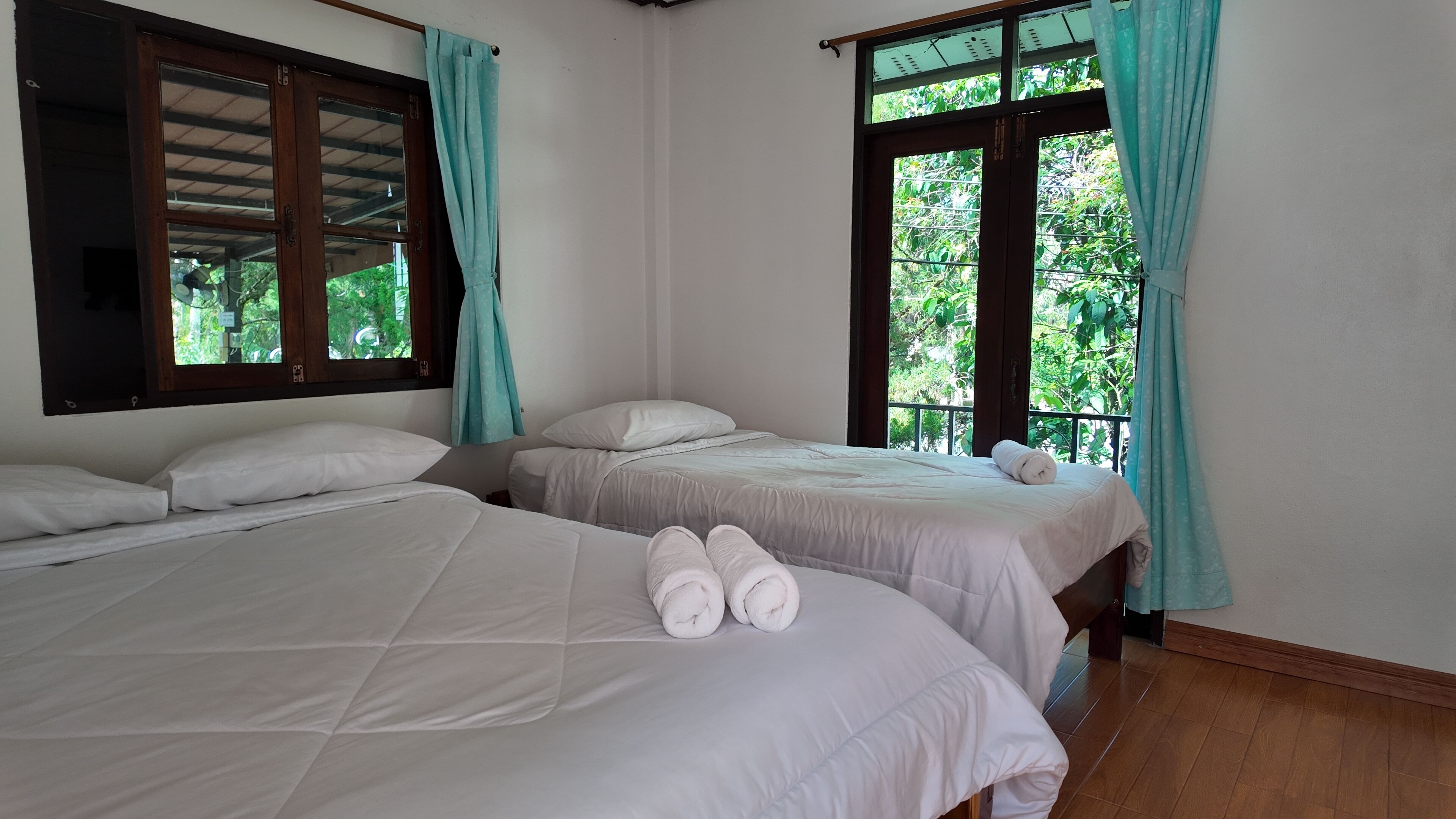 Habitación con dos camas, cada una con ropa de cama y almohadas blancas, y un par de toallas enrolladas sobre las camas.