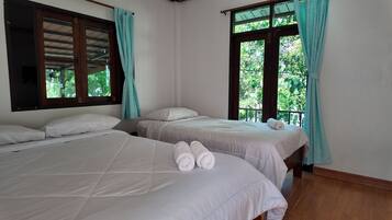 A room with two beds, each with white bedding and pillows, and a pair of rolled towels on the beds.