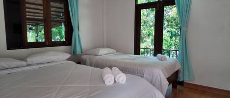 Habitación con dos camas, cada una con ropa de cama y almohadas blancas, y un par de toallas enrolladas sobre las camas.