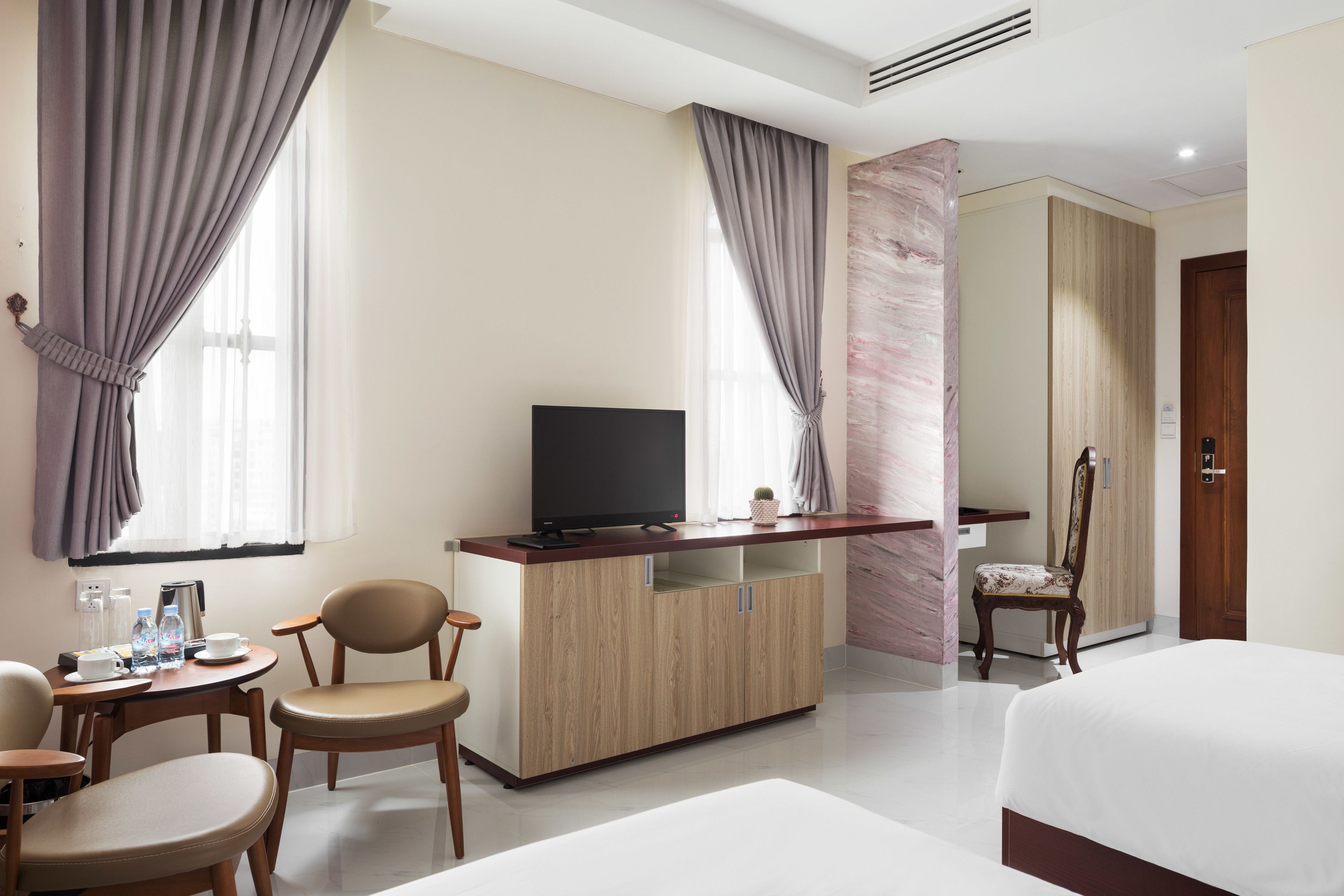 Une chambre d’hôtel comprenant un lit, une télévision, un bureau avec une chaise et une armoire.