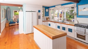 A kitchen with white cabinets, a wooden countertop, and a built-in oven. - Beach House Cairns (Holloways Beach)