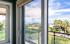 Un balcon offrant une vue sur un paysage côtier, comprenant une colline et des bâtiments.