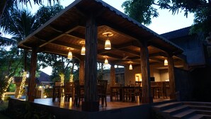 An outdoor covered patio area with wooden furniture and hanging lights. - The Inn by Sunsethouse (Senggigi)