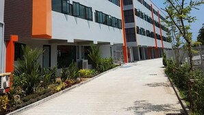 A modern multi-story building with a central courtyard, featuring a mix of glass and solid panels, and a prominent orange accent wall. - Samui City Hotel (Koh Samui)