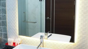 A bathroom with a white sink, a glass shower enclosure, and a dark wooden cabinet. - Samui City Hotel (Koh Samui)