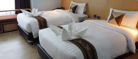 A hotel room with two beds, each with white linens and decorative pillows.