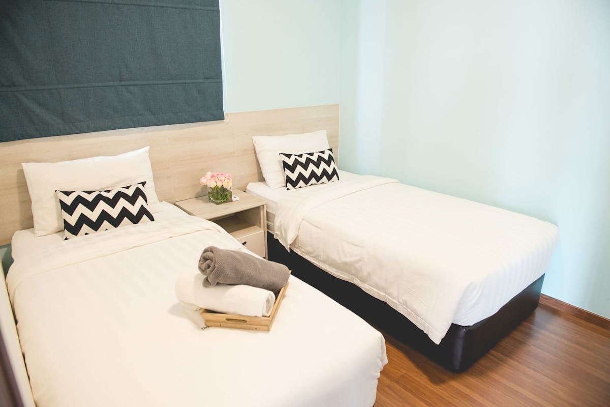 A double room with two beds, each with a pillow and a nightstand.