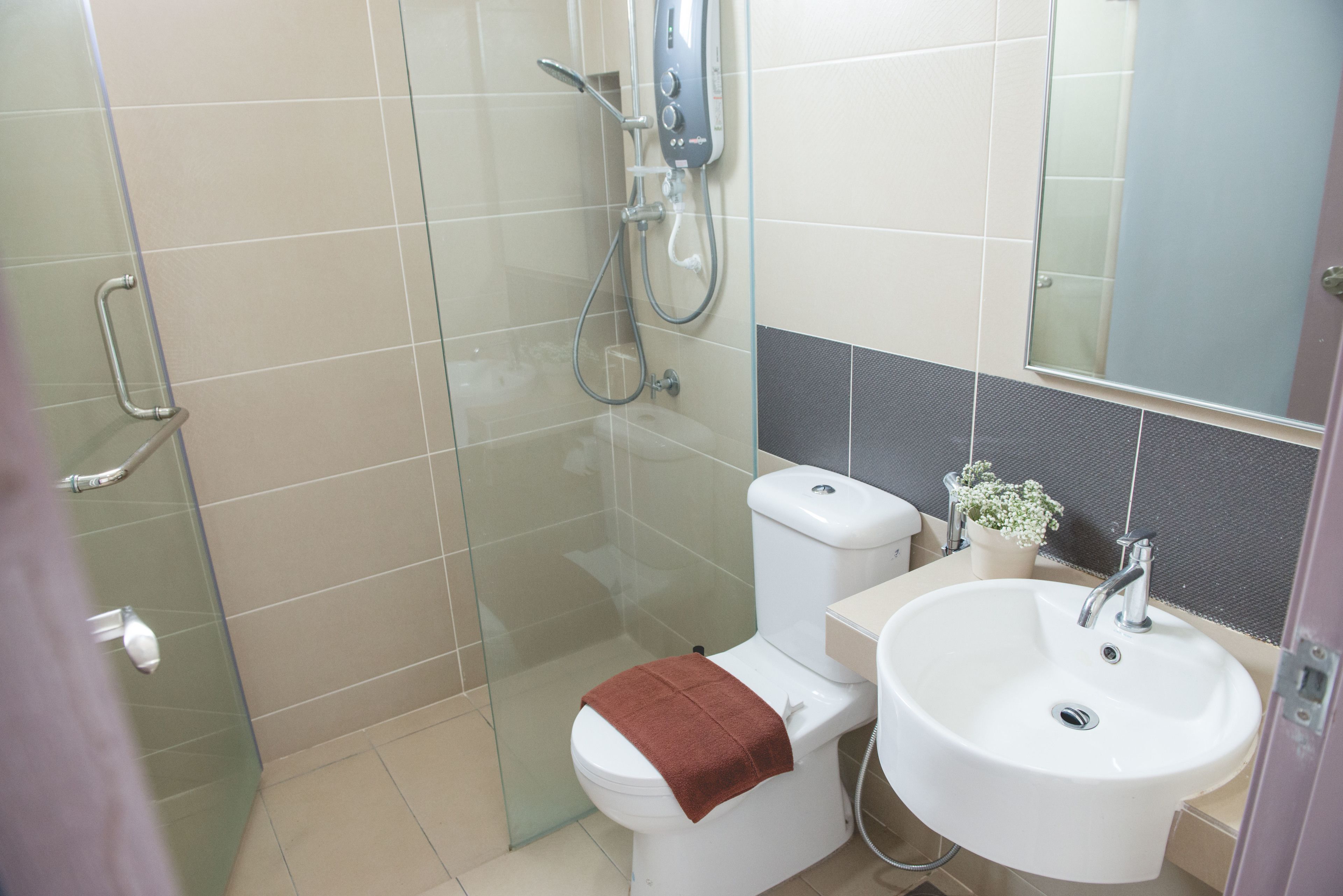 A bathroom with a glass shower enclosure, a toilet, a sink, and a mirror.