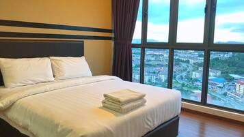 Ein Hotelzimmer mit einem großen Bett, Blick auf eine Stadtlandschaft durch ein Fenster und einem Vorhang.