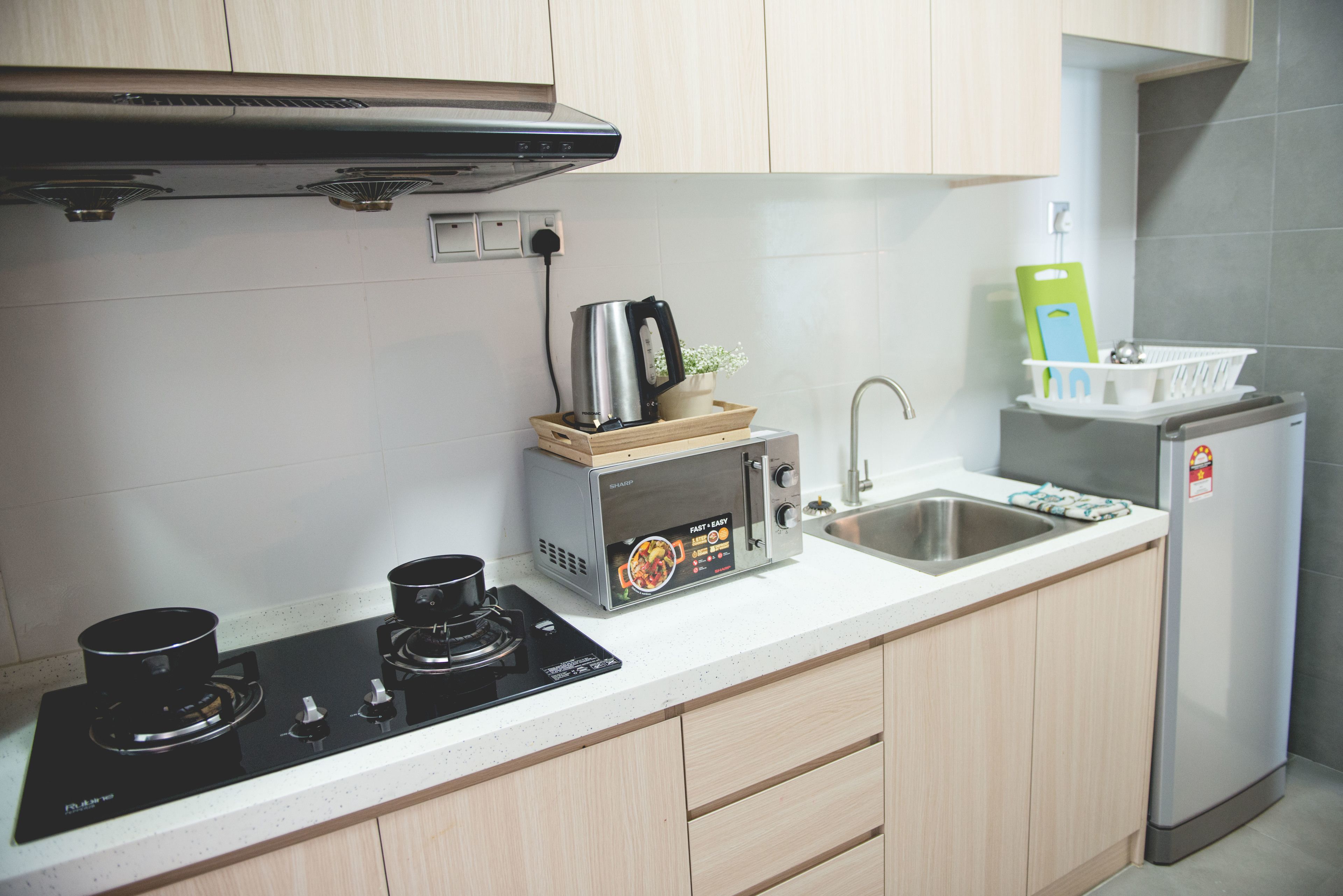 Una cocina equipada con estufa, microondas, pileta y refrigerador.