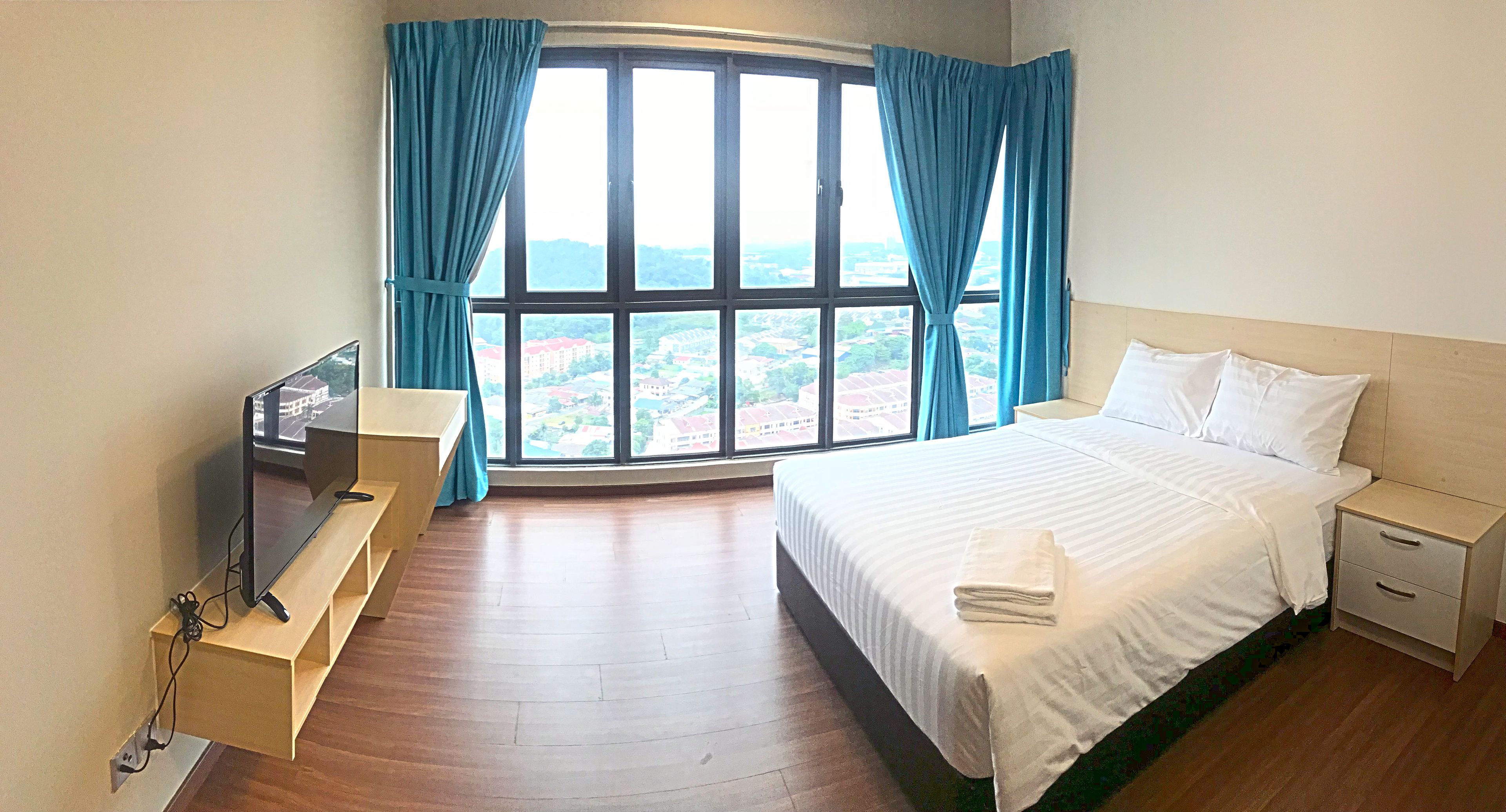 Een hotelkamer met een groot raam, een bed, een nachtkastje en een televisie op een standaard.