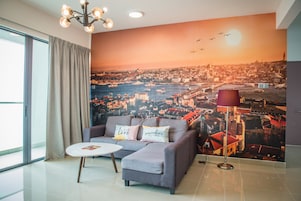 A modern living room with a gray sofa, a small white table, and a cityscape mural on the wall.