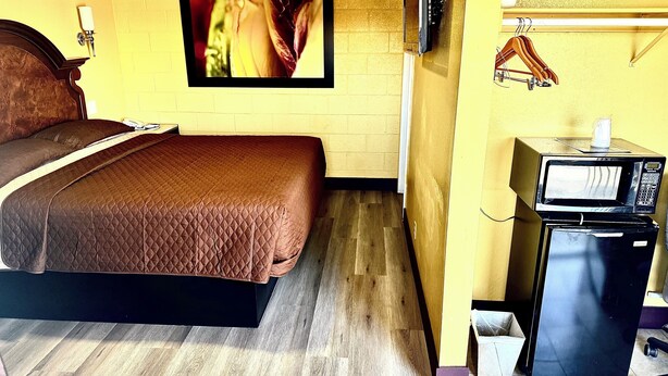 Een kamer met een bed, een wandtelevisie, een magnetron en een kleine koelkast.