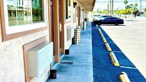 Een motel met een overdekte doorgang, een parkeerplaats en palmbomen op de achtergrond.