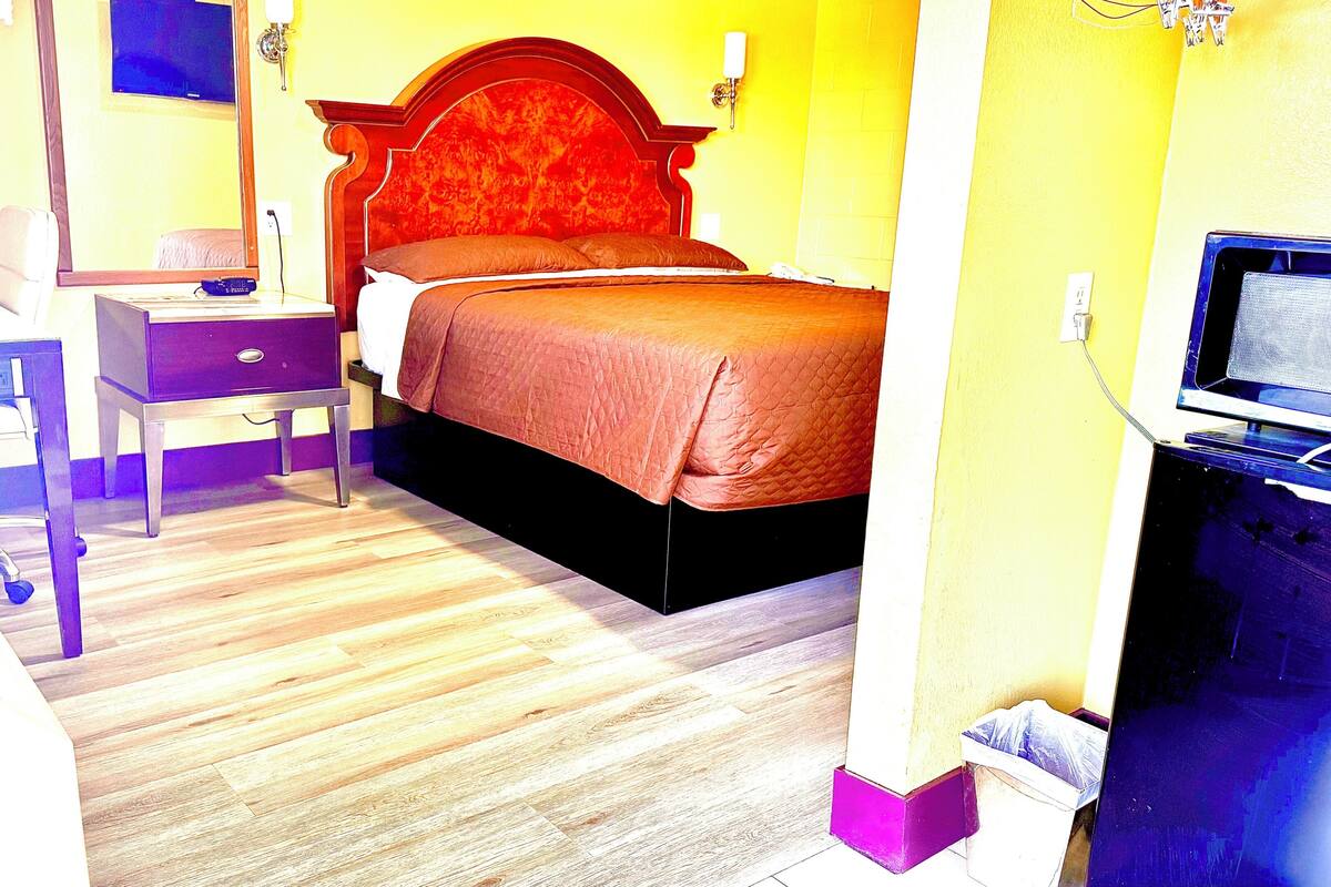 A hotel room with a bed, a desk, a chair, and a television.