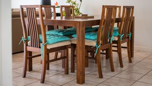 Een eettafel met vier houten stoelen, elk voorzien van teal kussens en vastgebonden met teal linten.