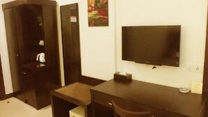 A hotel room with a dark wooden desk, a flat-screen TV mounted on the wall, a small bedside table, and a chair. - My Inn Hotel Lahad Datu, Sabah (LAHAD DATU)