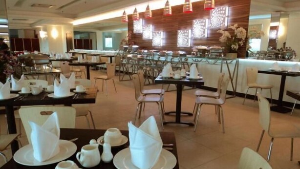 A dining area with tables set for breakfast, including plates, cups, and cutlery. - My Inn Hotel Lahad Datu, Sabah (LAHAD DATU)