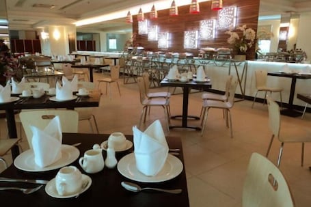 A dining area with tables set for breakfast, including plates, cups, and cutlery.