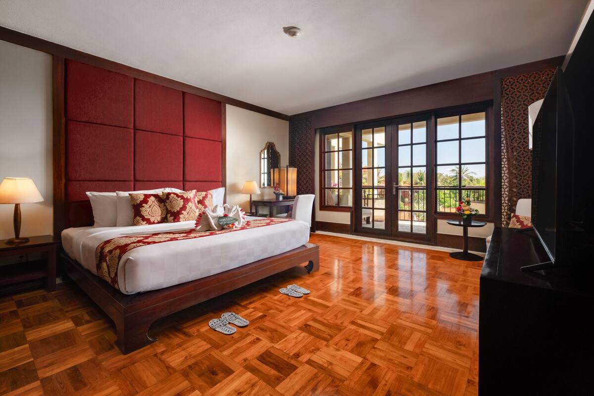 Une chambre spacieuse avec un grand lit, un plancher en bois, une grande fenêtre donnant sur un beau paysage et un téléviseur.