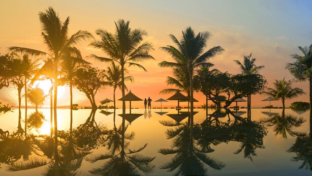 Une plage paisible, avec des palmiers et un coucher de soleil.