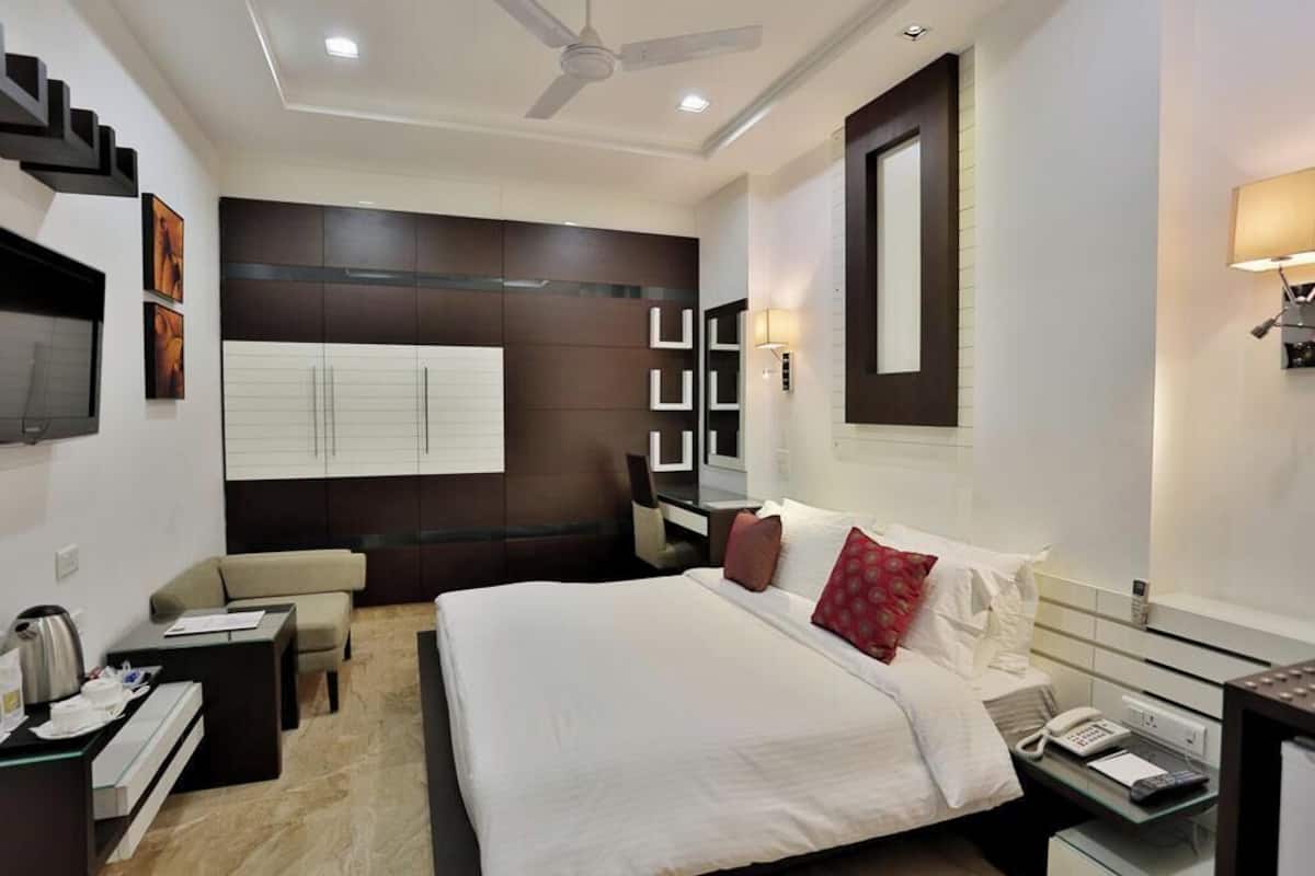 A modern hotel room with a bed, bedside table, desk, chair, and a ceiling fan.
