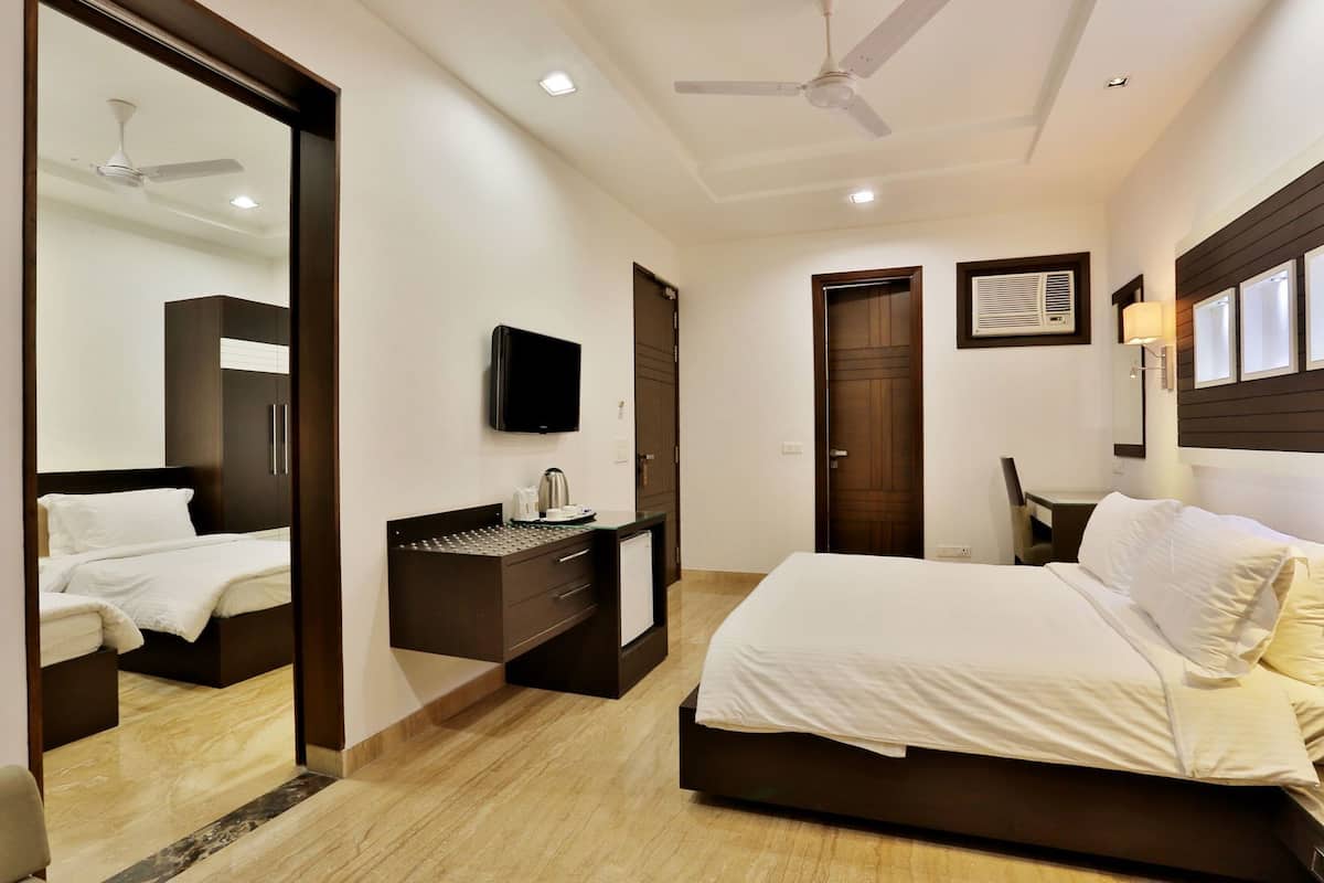 A hotel room with a bed, a desk, a television, a mirror, and a ceiling fan.
