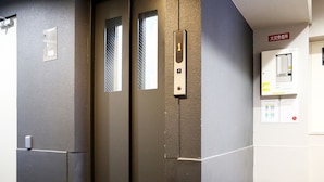 An elevator with a metallic door and a control panel with a button. - JL Residence Hotel (Osaka)