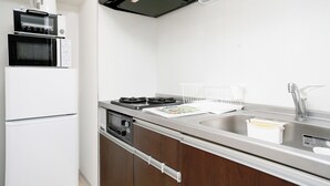 A modern kitchen with a built-in microwave, oven, and dishwasher, a stainless steel sink, and a gas stove. - JL Residence Hotel (Osaka)