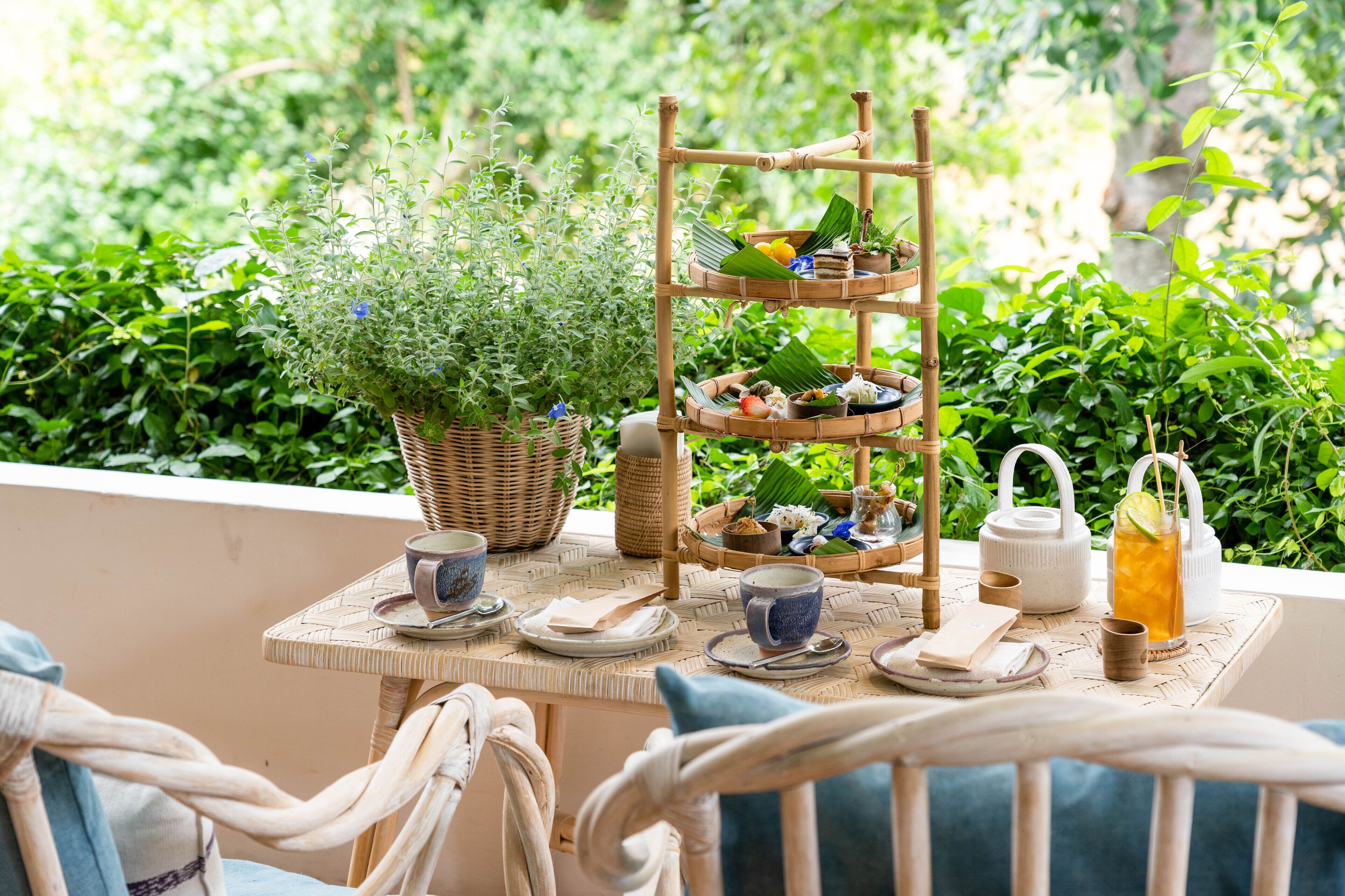 A table set with a wicker basket, a tiered tray, and a potted plant.
