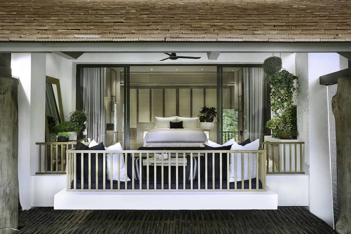 A bedroom with a bed, pillows, a ceiling fan, and a view of the outdoors.