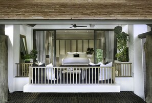 A bedroom with a bed, pillows, a ceiling fan, and a view of the outdoors.