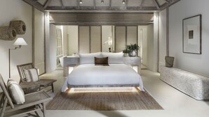 A spacious bedroom with a large bed, a sitting area with chairs, a bedside table, and a bench. - Raya Heritage (Mae Rim)
