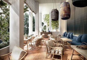 A spacious outdoor seating area with wicker furniture, hanging lanterns, and a view of greenery.