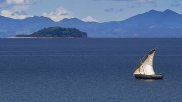 A sailboat on calm waters with a mountainous island in the background.