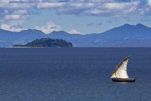 A sailboat on calm waters with a mountainous island in the background.